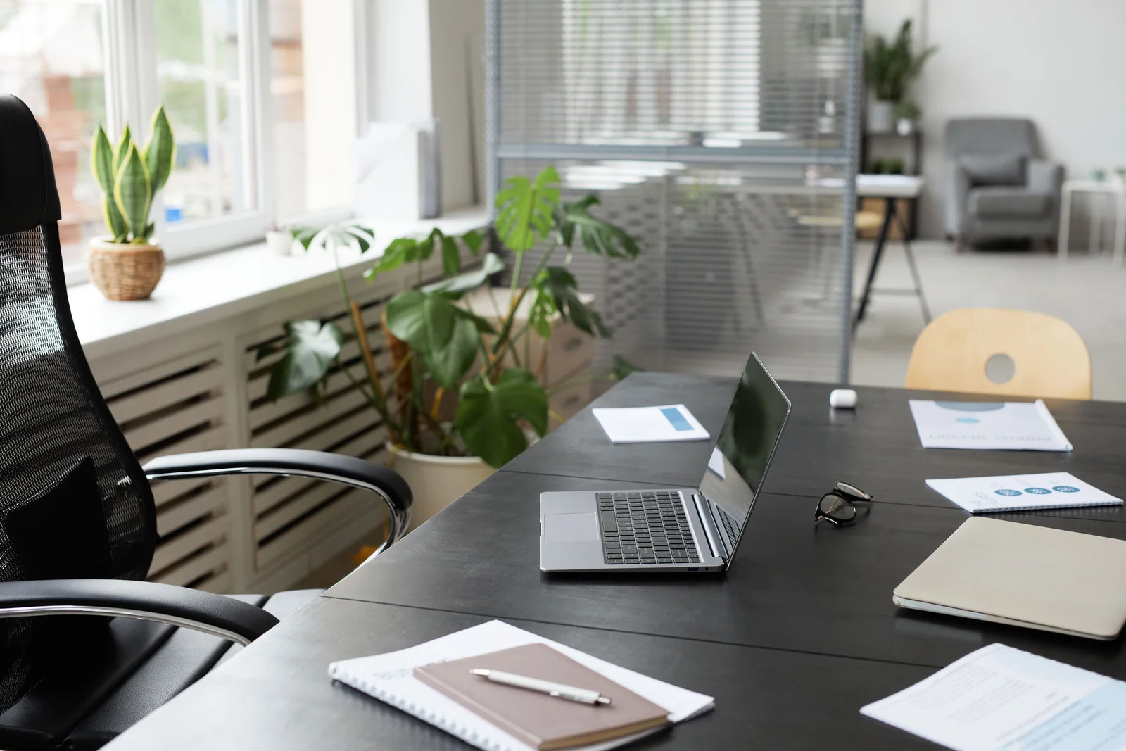 Laptop aberto sobre uma mesa com cadernos e plantas