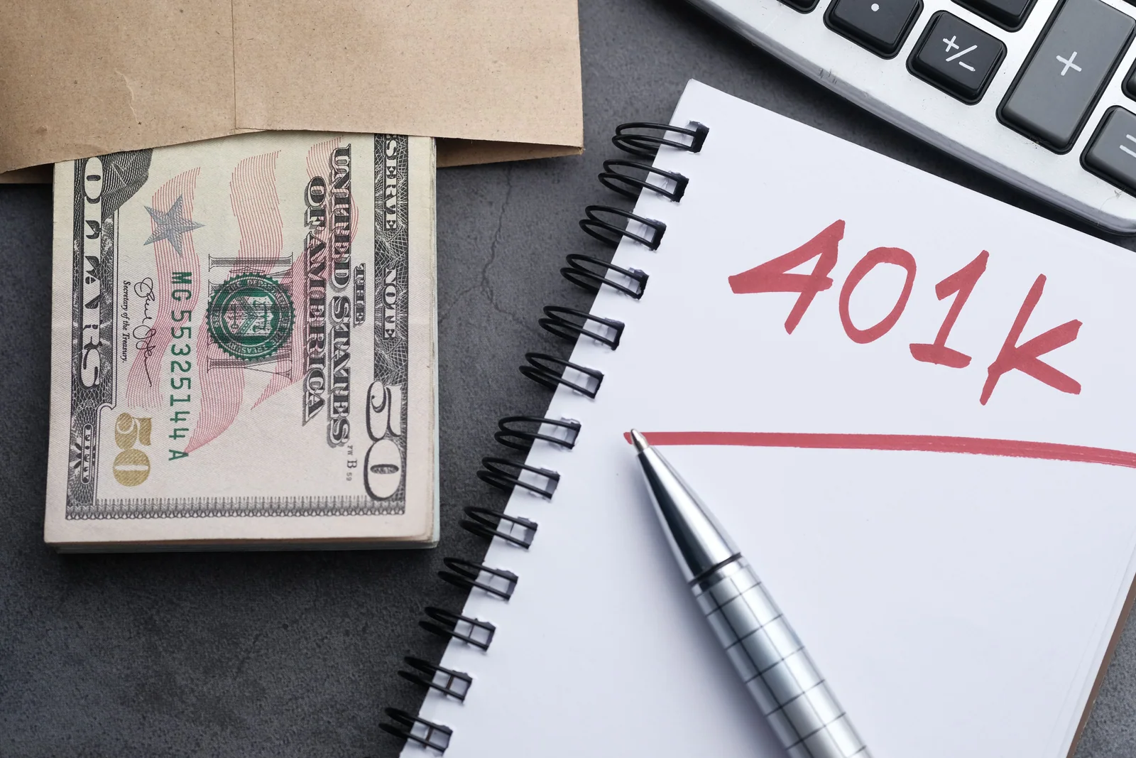 Dinheiro e caderno com referência a 401(k)