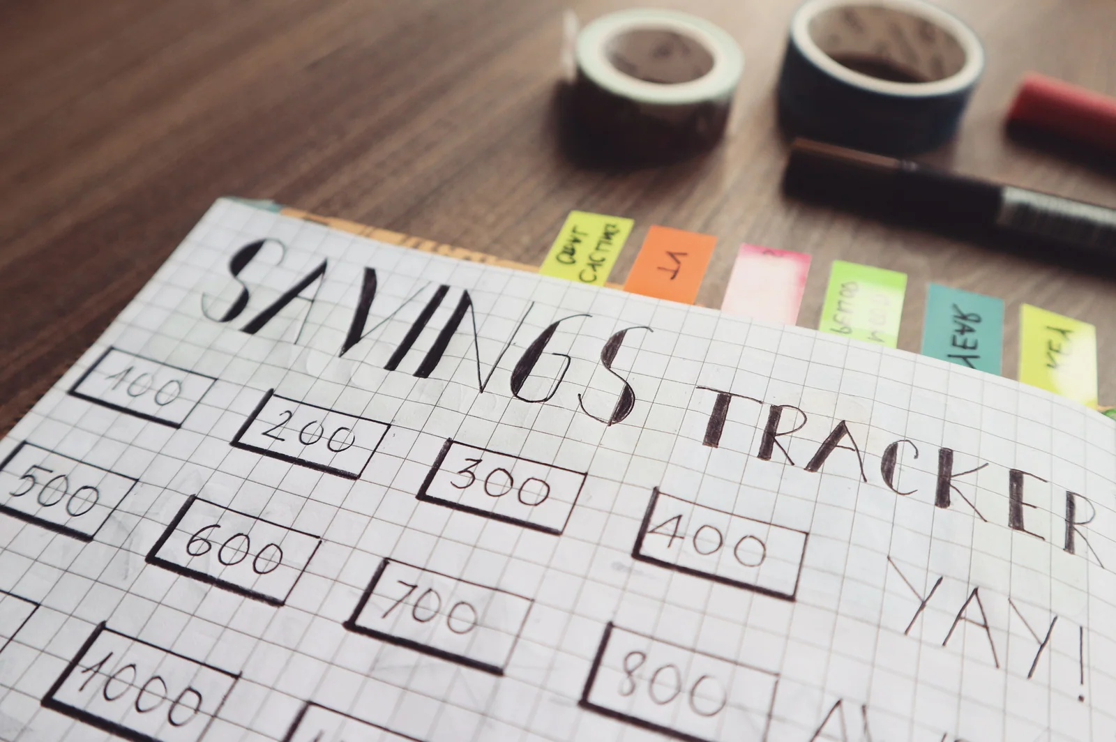Caderno de planejamento financeiro com moedas e caneta sobre uma mesa