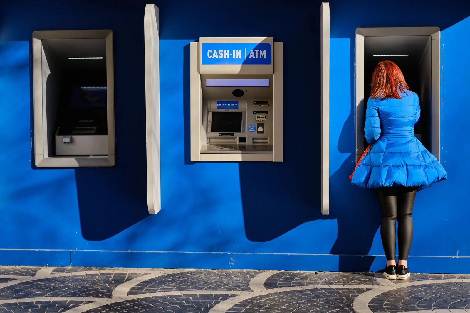 Pessoa usando um caixa eletrônico em uma área com vários ATMs