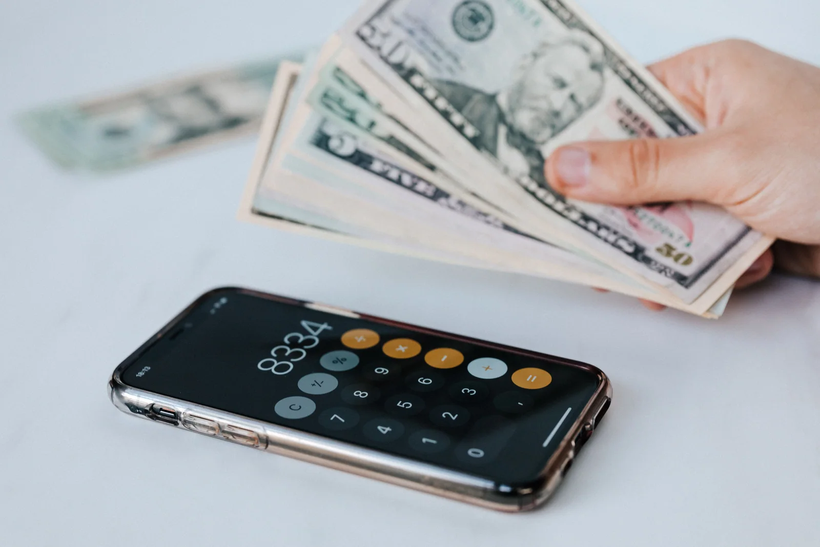Dólares ao lado de uma calculadora aberta no celular