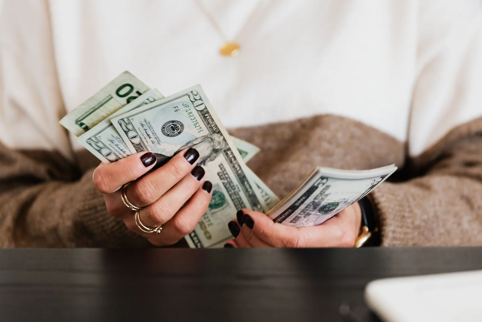 Mãos contando dólares, o valor que o salário deveria colocar na conta