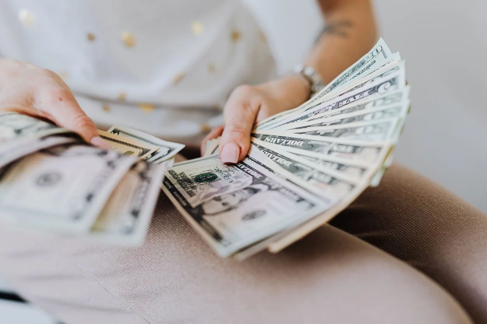 Pessoa conferindo cédulas de dólar antes de um pagamento