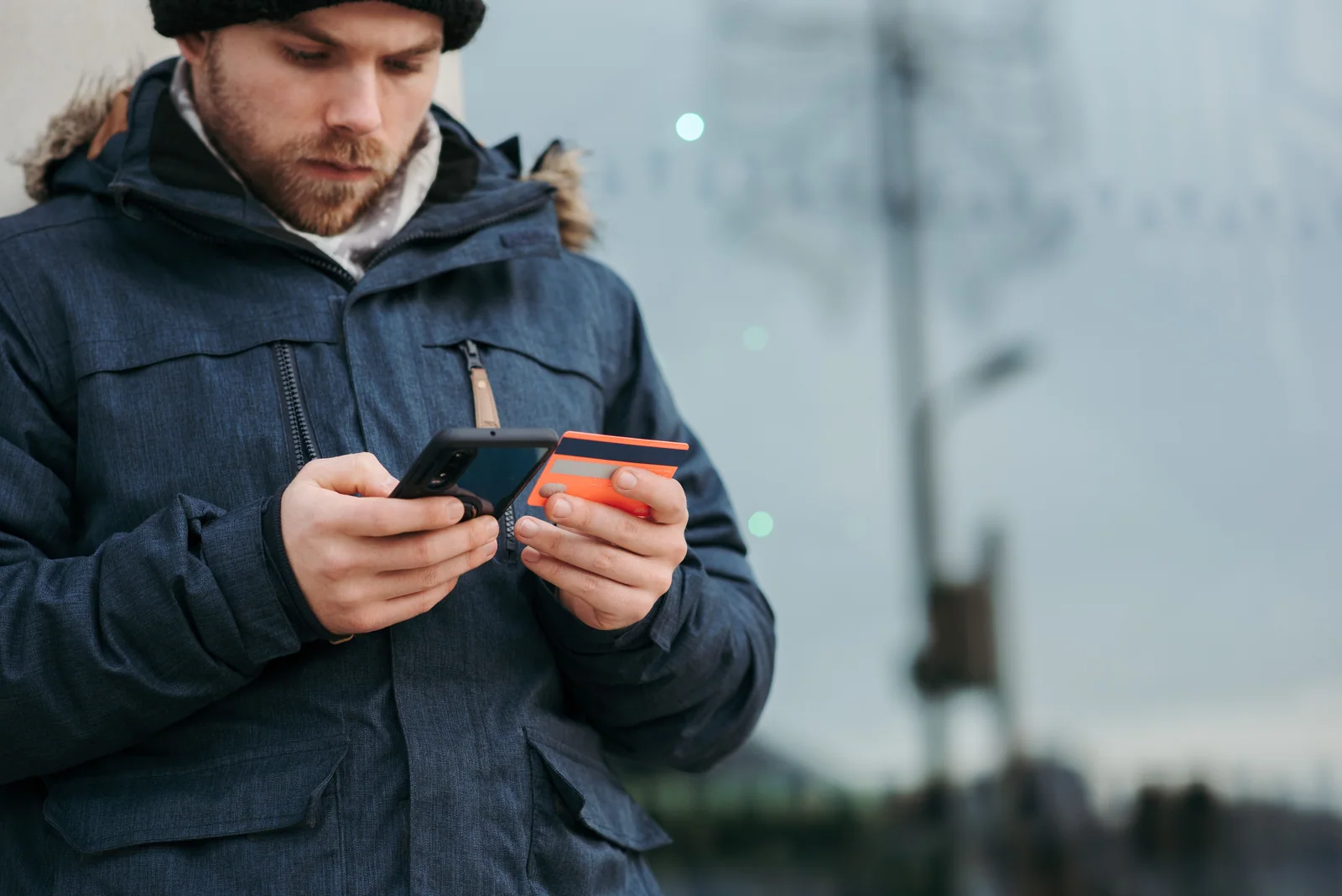 Pessoa usando o celular enquanto segura um cartão bancário
