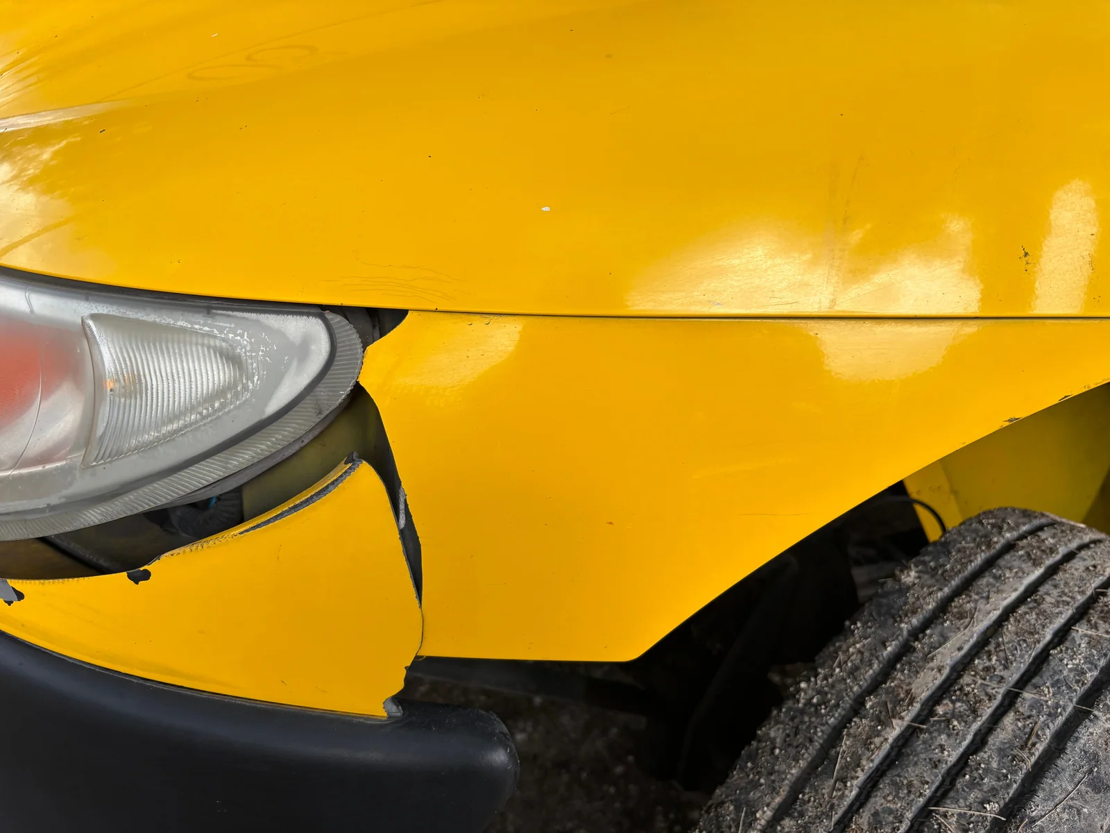 Parte dianteira de um carro amarelo danificada em uma colisão