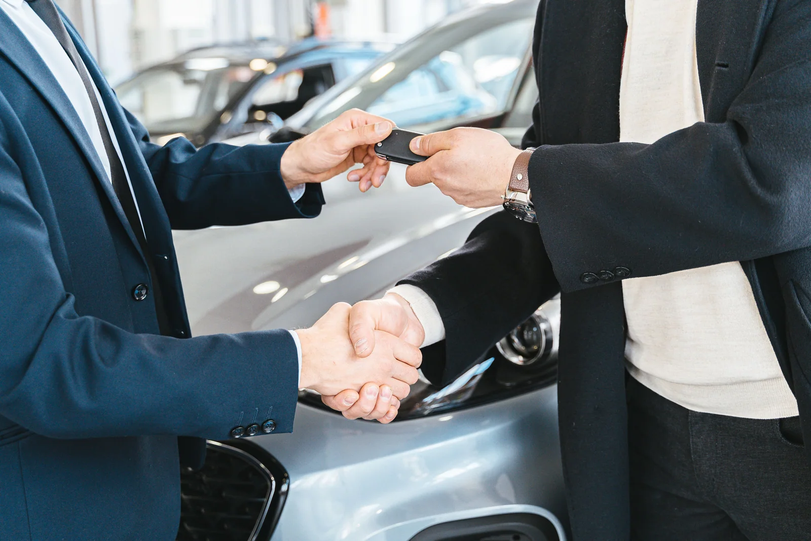 Vendedor entregando a chave de um carro a uma compradora
