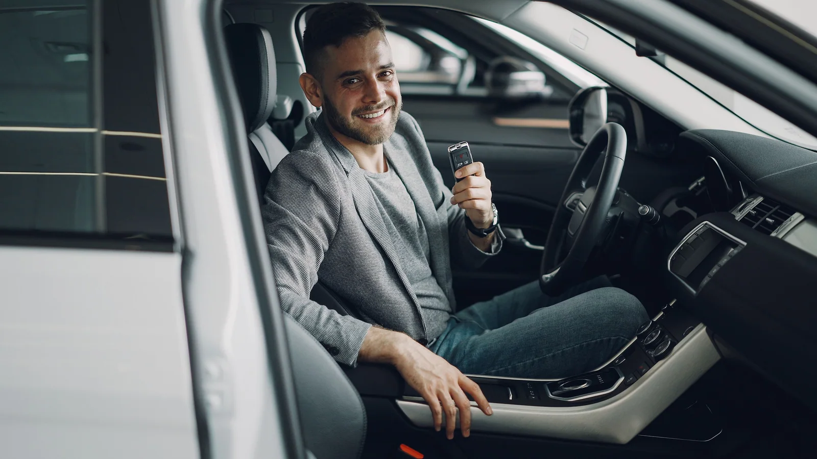 Motorista dentro de um carro segurando a chave do veículo