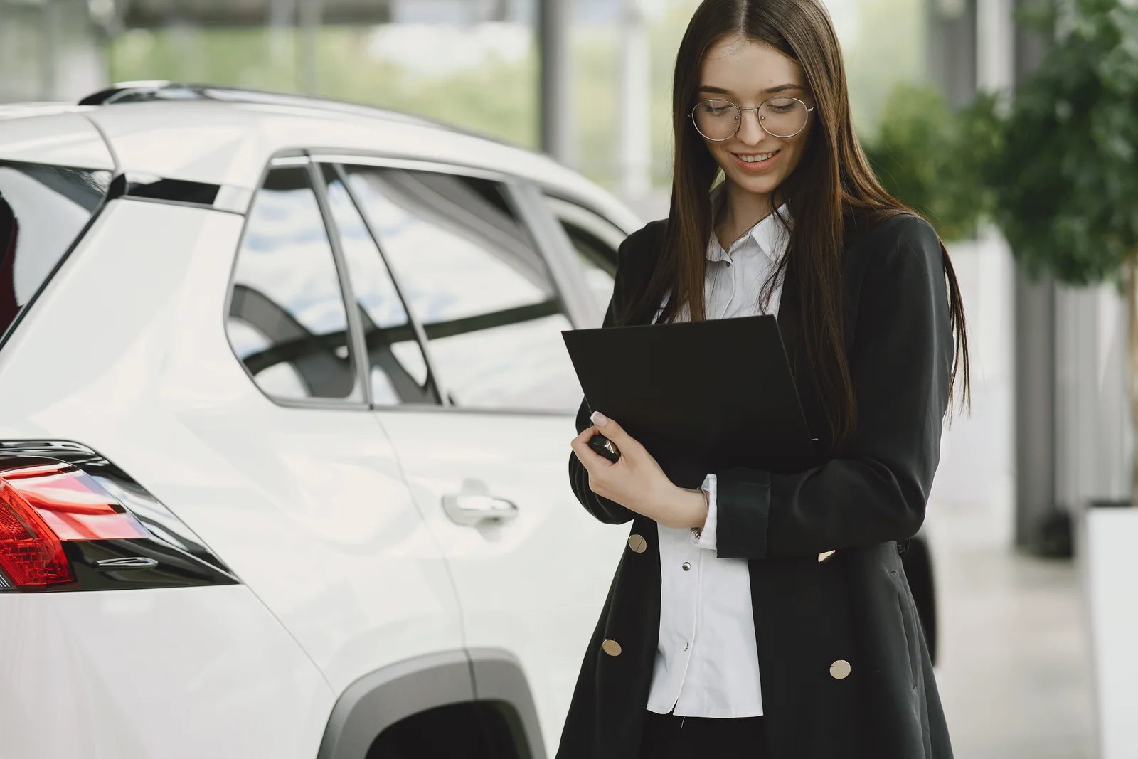 Profissional conferindo documentos ao lado de um carro