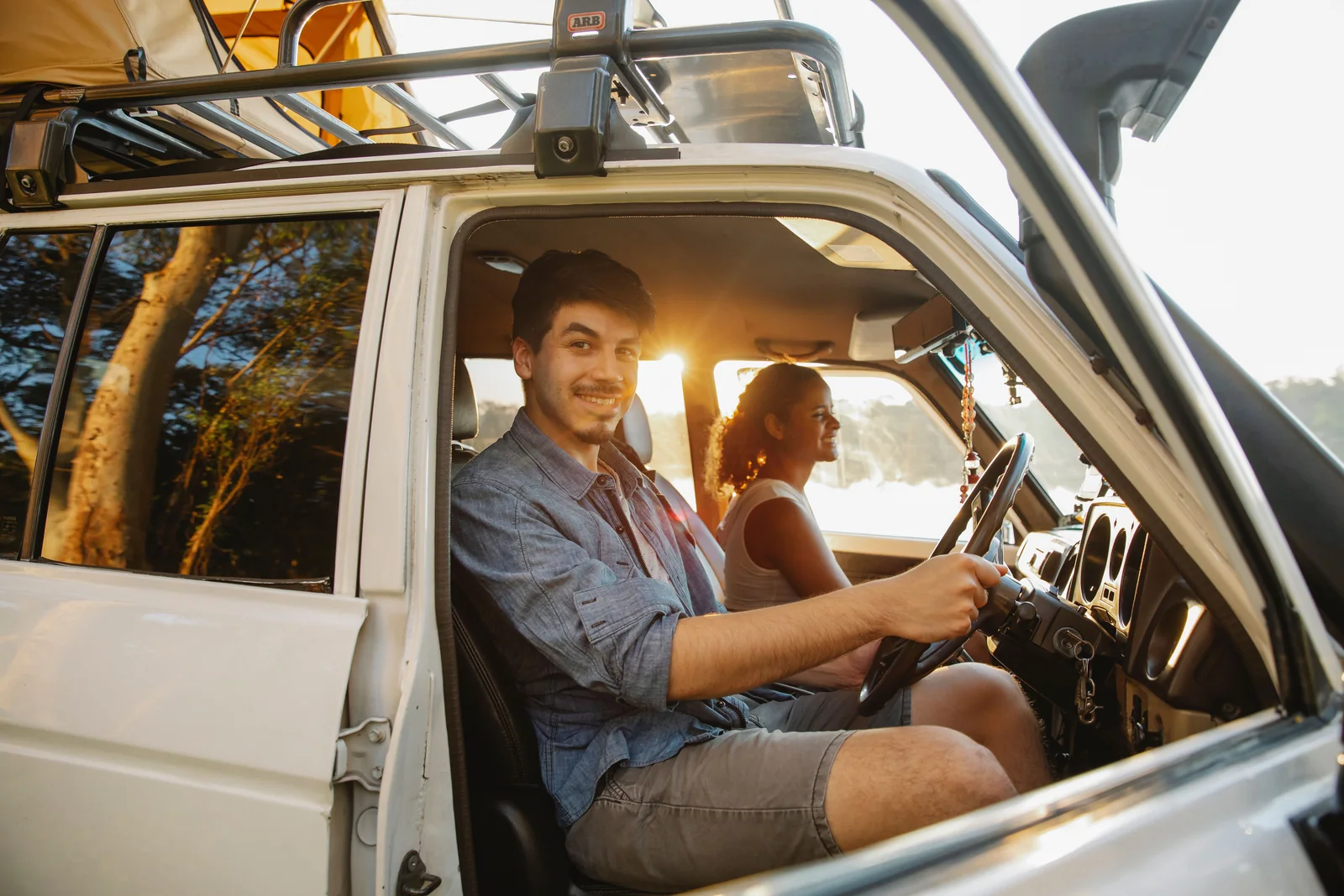 Casal sorrindo dentro de um carro parado com a porta aberta, o passeio que ainda não é o título no nome de quem comprou