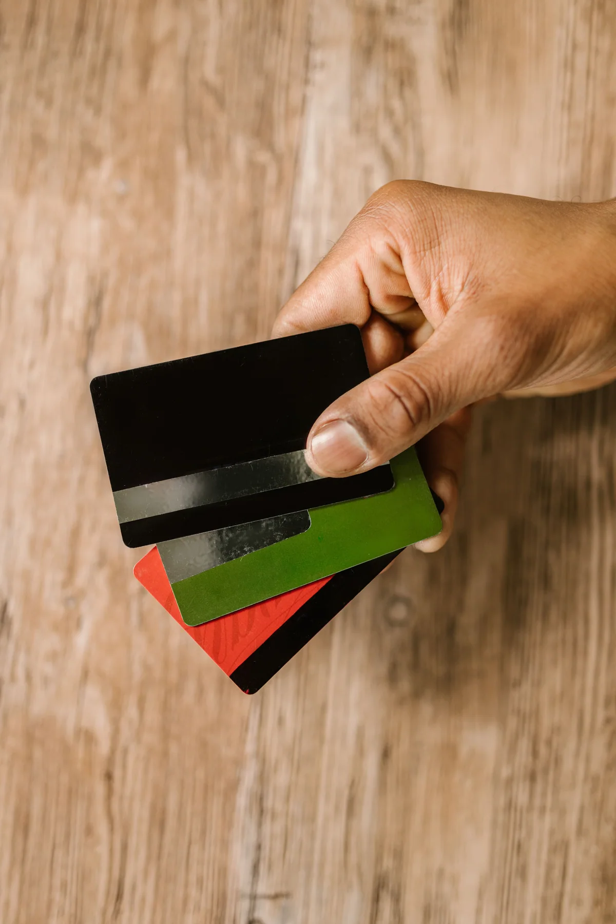Mão segurando três cartões de crédito genéricos espalhados