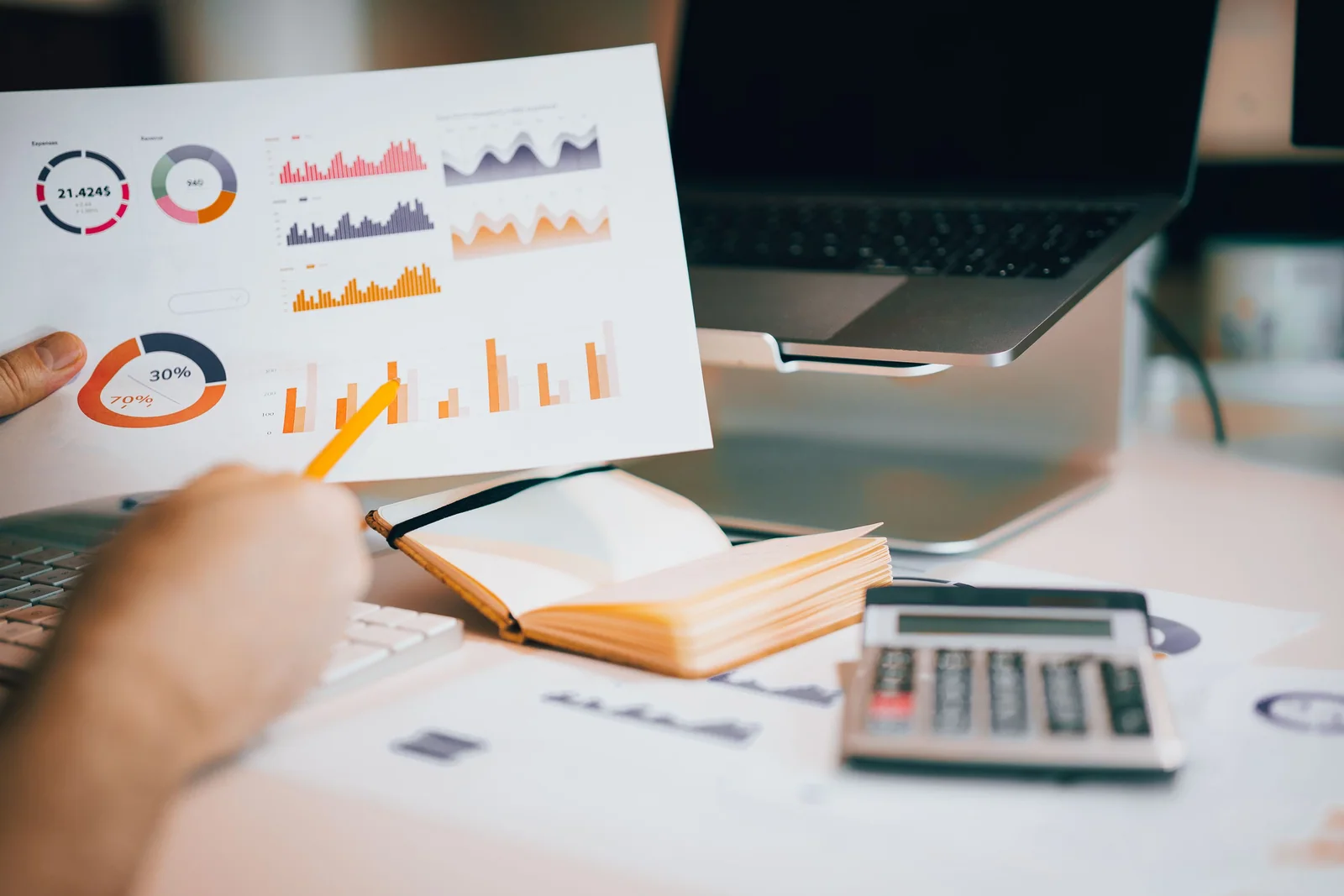 Pessoa analisando gráficos financeiros ao lado de um computador