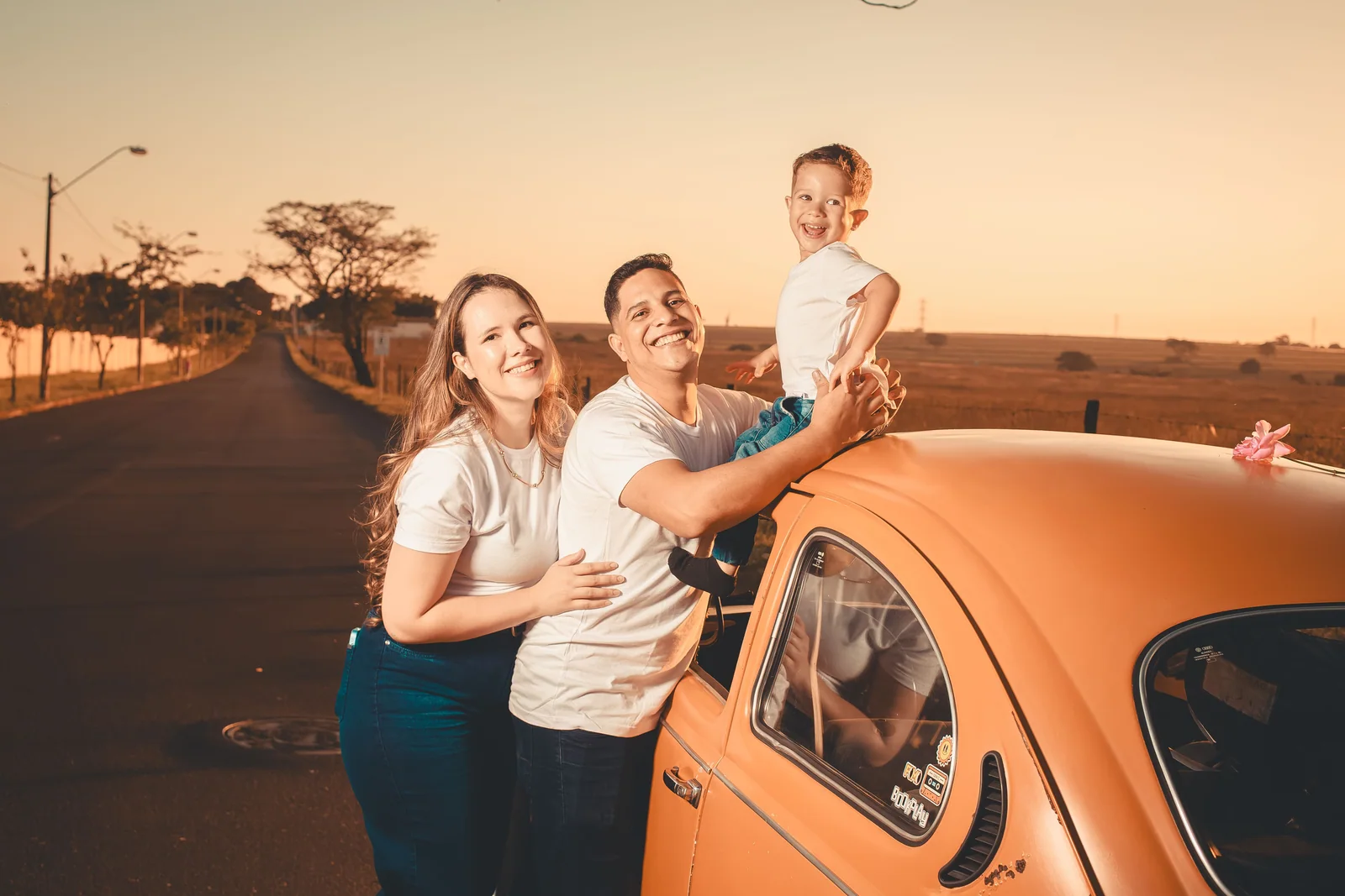 Família ao lado de um Fusca numa estrada ao entardecer