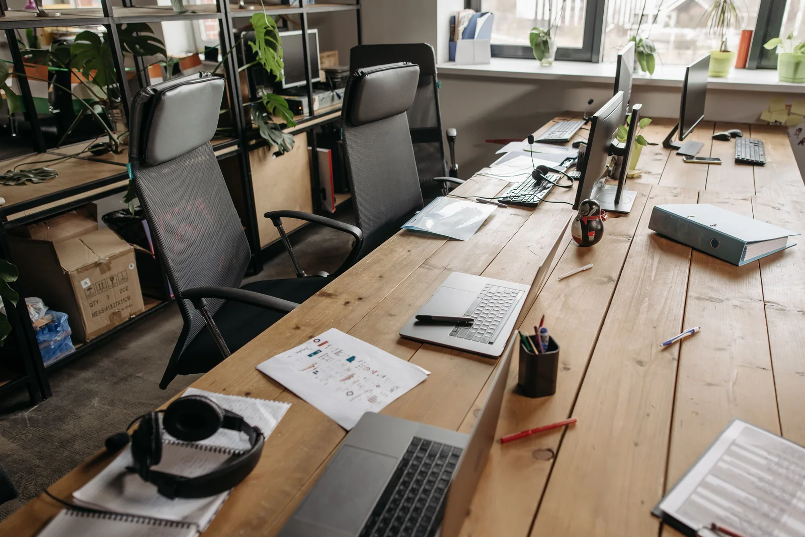 Mesa de trabalho com laptops e papéis, o tipo de espaço onde se lê um prospecto