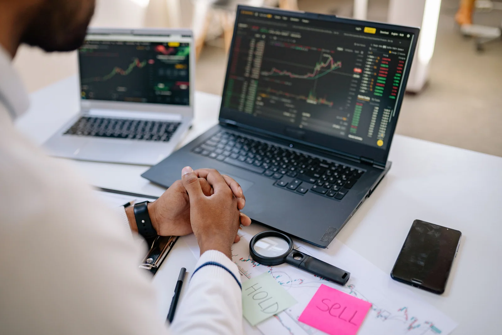 Dois monitores com gráficos de mercado em uma mesa de trabalho