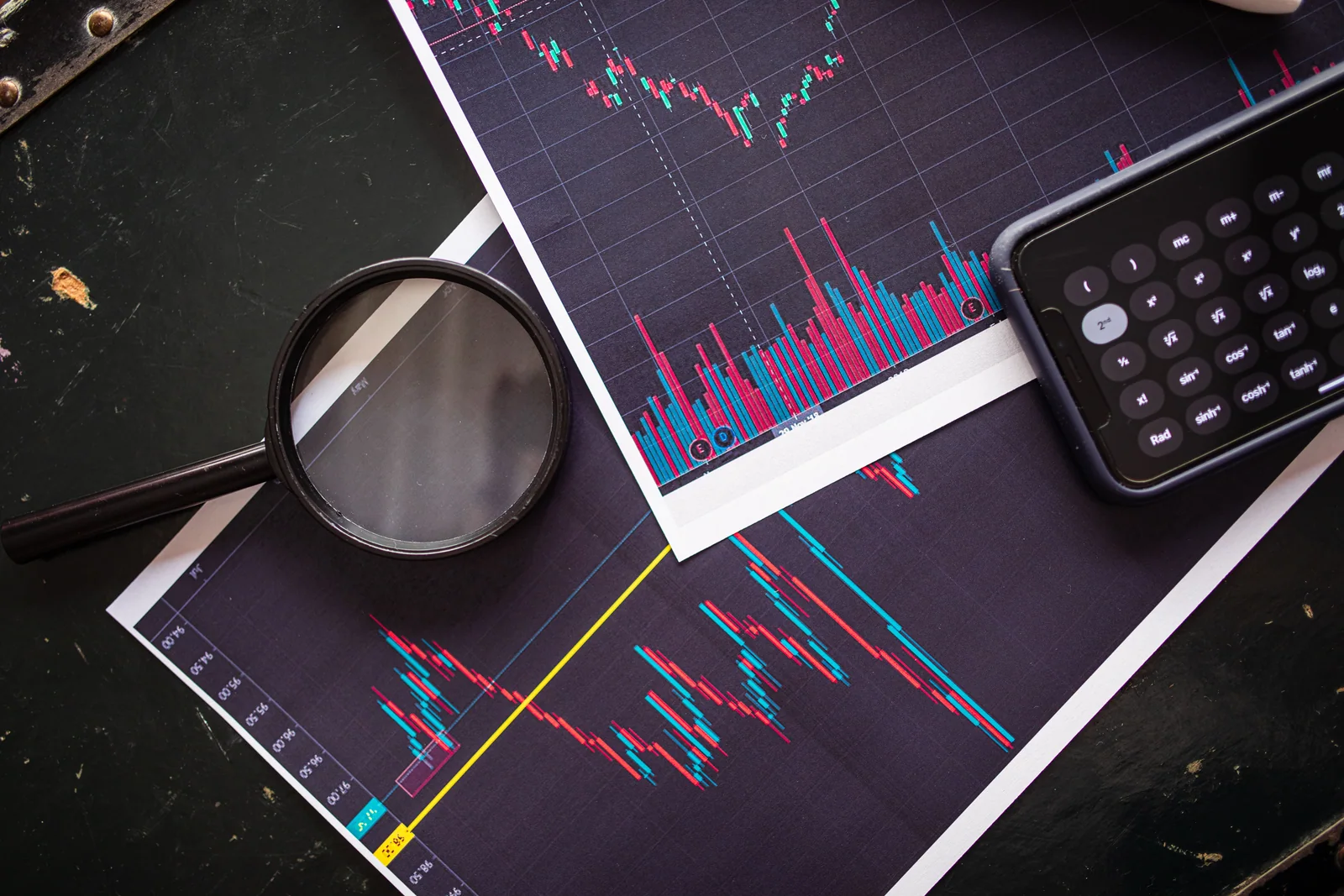 Gráficos impressos com calculadora e lupa usados para analisar uma carteira