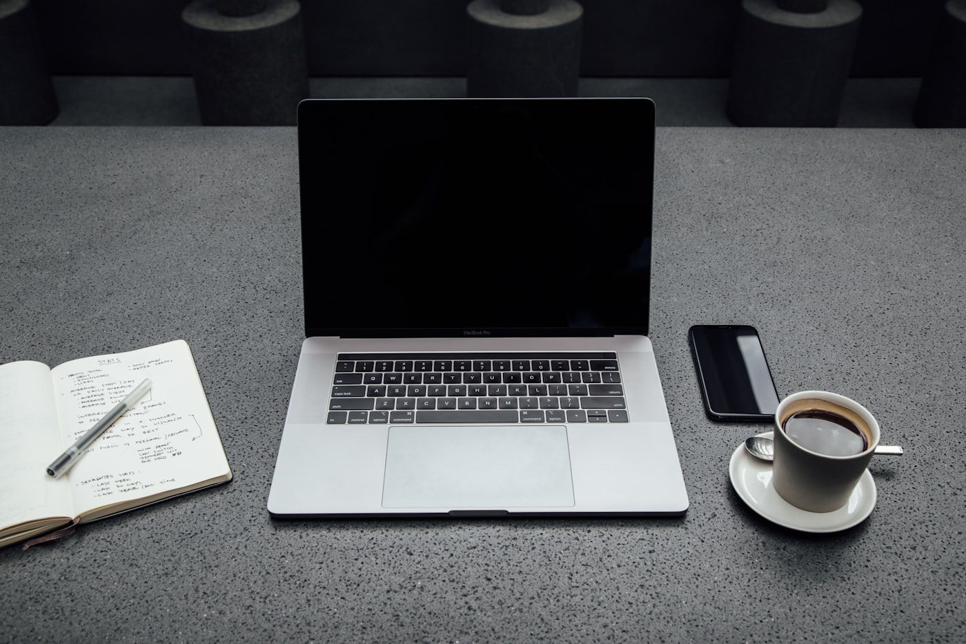 Mesa de trabalho organizada com laptop, caderno de anotações e café